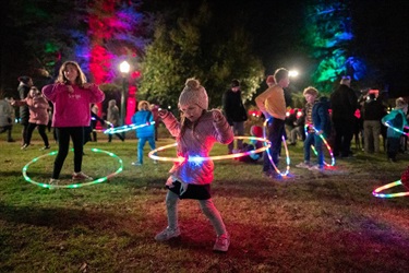 Children hoola hooping with the lit up LED hoola hoops at night time in the park.