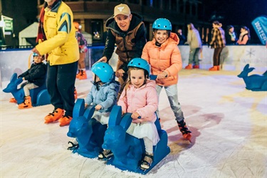 A dad and three kids skating together on the McDonald's Bathurst Ice Rink.