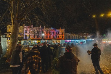 Illuminated 179 George Street with smoking ceremony and welcome to country taking place in front.