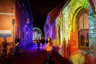 Illuminated Ribbon Gang Lane looking out towards the festival and the lit up Ferris wheel.
