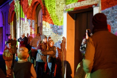 People posing for photos in front of the illuminated walls of Ribbon Gang Lane.