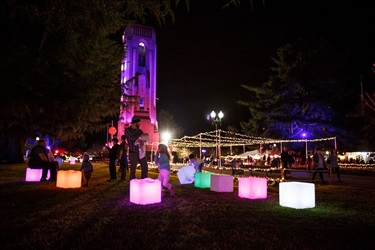 Families enjoying the park at nighttime with fun glowing installations.