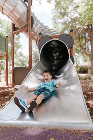 Boy sliding down a metal slide in the Cameron Park.