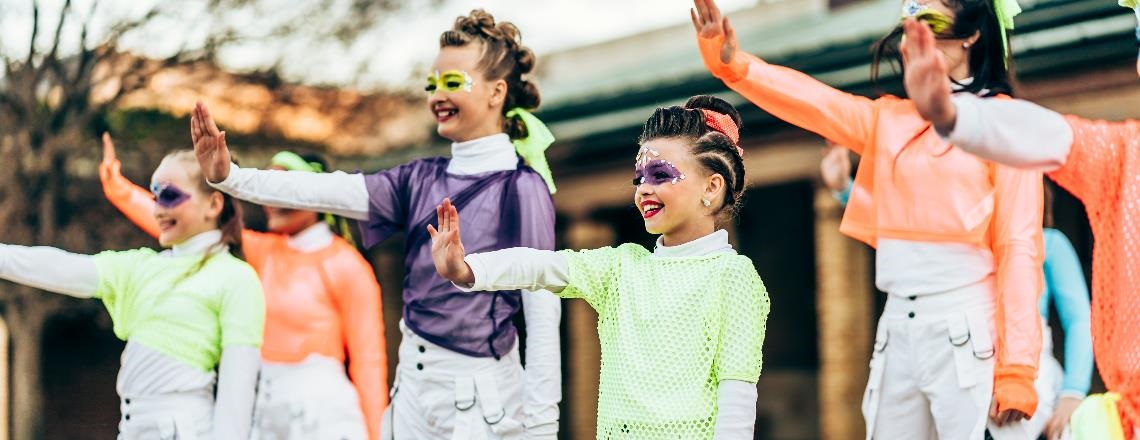 Dance group dressed in neon colours performing.