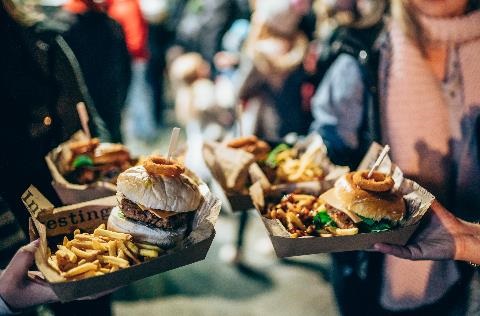 Four people holding together their boxed burger meals.